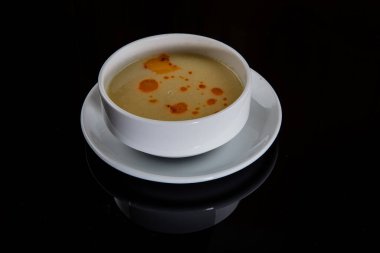 Mercimek çorbası (Türkçe: Mercimek Corbasi) siyah zemin üzerinde izole edilmiş.