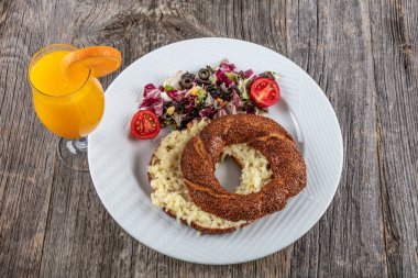 Tahta arka planda simitli ve sebzeli kahvaltı.