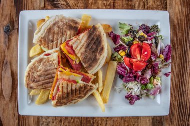 Patates kızartmalı hamburger ve ahşap arka planda sebze salatası.