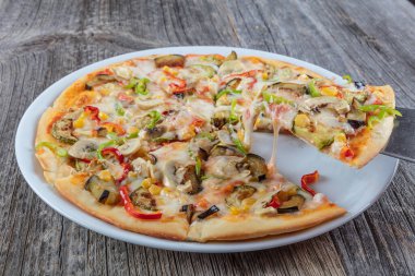 Sıcak pizza dilimi, erimiş peynirle ahşap bir masada..