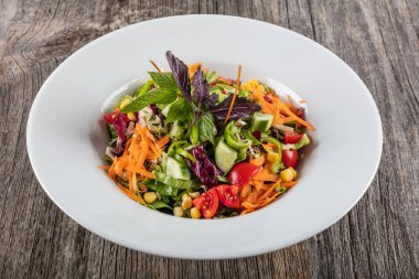 Tahta arka planda sebzeli ve peynirli salata.