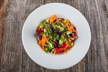 Tahta arka planda taze sebzeli salata.