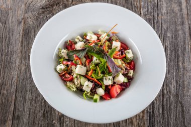 Tavuklu salata, domates ve beyaz tabakta beyaz peynir. en üstteki görünüm.