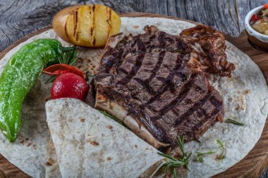 Sebzeli ızgara biftek ve ahşap tahtada sos.