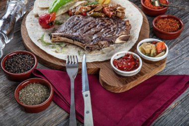 Sebzeli biftek ve ahşap masada baharat.