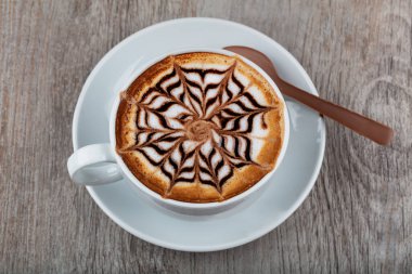 Beyaz kremalı, ahşap arka planda bir fincan kahve. 