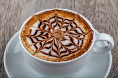 Beyaz kremalı, ahşap arka planda bir fincan kahve. 