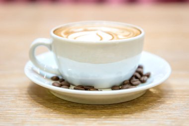 Tahta masada köpüklü bir fincan kahve.