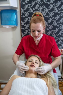 Güzellik uzmanının eli. Güzellik kliniğindeki genç ve çekici bayan müşterinin reşit olmama prosedürünü, maskesini ve kabuğunu çıkarıyor. Cilt bakımı uzmanı. Sağlık terapisi..