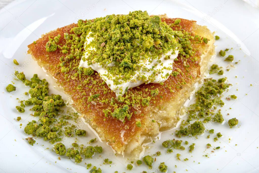 Turkish dessert kunefe, kunafa, kadayif with pistachio powder and cheese hot eaten a sweet.