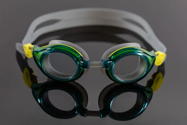 Swimming goggles (pool goggles) and reflection on black backdrop.