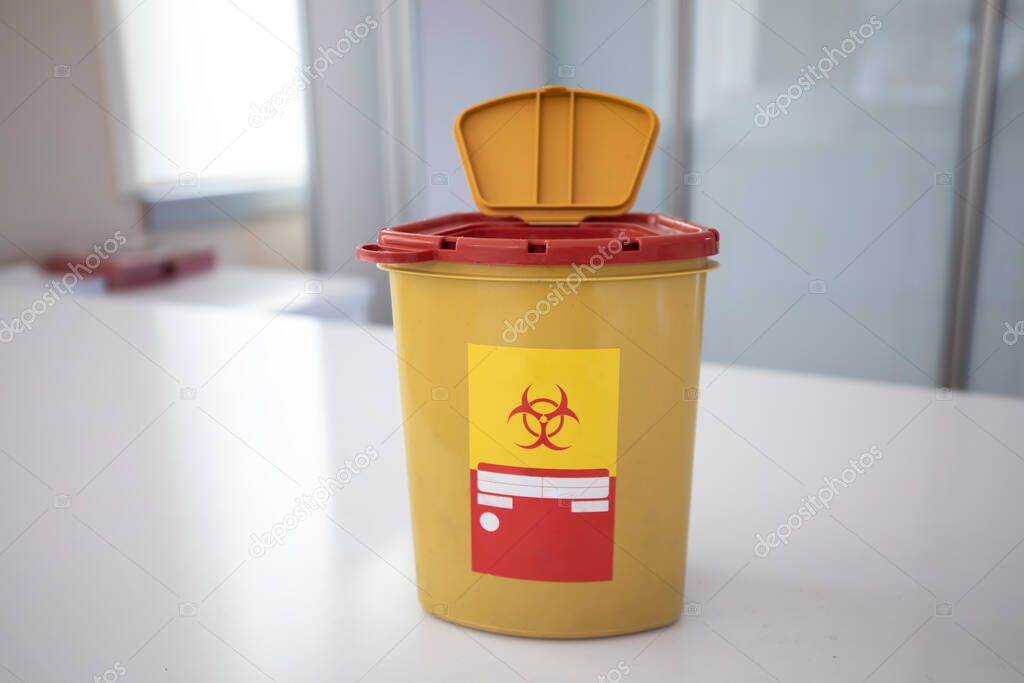 Yellow biohazard medical contaminated sharps clinical waste container isolated on white background.