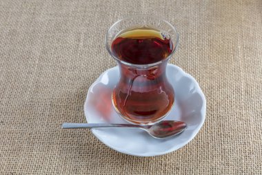 Bir fincan çay, bir kaşık ve ahşap arka planda bir bardak kırmızı şarap.