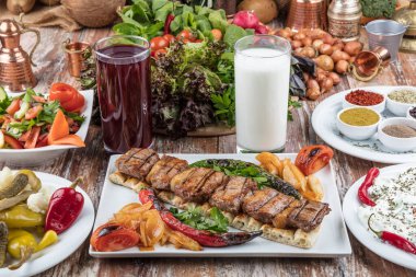 Ahşap masada sebzeli ve soslu lezzetli ızgara et.