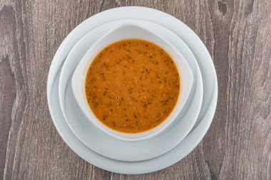 top view of a bowl of white sauce with a cup of coffee on a wooden background