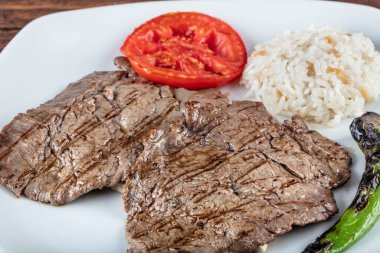 Orta pişmiş sığır filetosu ızgara, ahşap arka planda sebzelerle arka plan oluşturuldu..