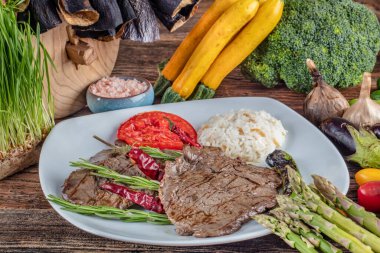 Orta pişmiş sığır filetosu ızgara, ahşap arka planda sebzelerle arka plan oluşturuldu..