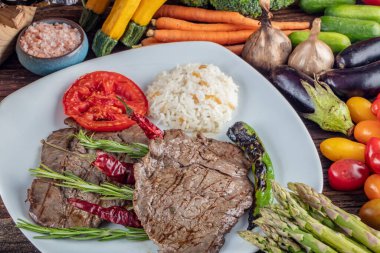 Orta pişmiş sığır filetosu ızgara, ahşap arka planda sebzelerle arka plan oluşturuldu..