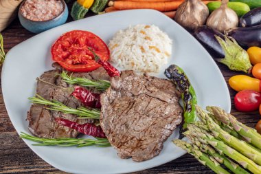 Orta pişmiş sığır filetosu ızgara, ahşap arka planda sebzelerle arka plan oluşturuldu..