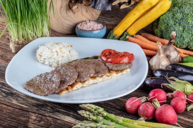 Orta pişmiş Türk köfteleri (Türk Gıda Kofte veya Kofta), ahşap zemin üzerinde sebzelerle arka plan oluşturdu. Türkçe adı: Sivas Kofte.