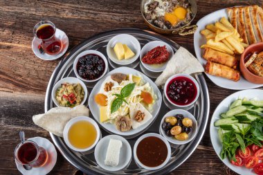 Geleneksel Türk kahvaltısı. İki kişilik kahvaltıyı ahşap zemine yayın (çifte kahvaltı tepsisi). Kahvaltı ya da brunch masası her çeşit lezzetli şarküteriyle dolu. Kahvaltı yayılıyor..