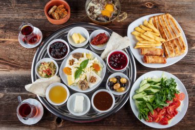 Geleneksel Türk kahvaltısı. İki kişilik kahvaltıyı ahşap zemine yayın (çifte kahvaltı tepsisi). Kahvaltı ya da brunch masası her çeşit lezzetli şarküteriyle dolu. Kahvaltı yayılıyor..