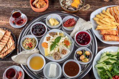 Geleneksel Türk kahvaltısı. İki kişilik kahvaltıyı ahşap zemine yayın (çifte kahvaltı tepsisi). Kahvaltı ya da brunch masası her çeşit lezzetli şarküteriyle dolu. Kahvaltı yayılıyor..