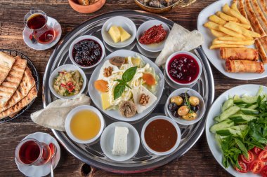 Geleneksel Türk kahvaltısı. İki kişilik kahvaltıyı ahşap zemine yayın (çifte kahvaltı tepsisi). Kahvaltı ya da brunch masası her çeşit lezzetli şarküteriyle dolu. Kahvaltı yayılıyor..