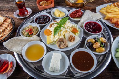 Geleneksel Türk kahvaltısı. İki kişilik kahvaltıyı ahşap zemine yayın (çifte kahvaltı tepsisi). Kahvaltı ya da brunch masası her çeşit lezzetli şarküteriyle dolu. Kahvaltı yayılıyor..