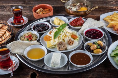 Geleneksel Türk kahvaltısı. İki kişilik kahvaltıyı ahşap zemine yayın (çifte kahvaltı tepsisi). Kahvaltı ya da brunch masası her çeşit lezzetli şarküteriyle dolu. Kahvaltı yayılıyor..