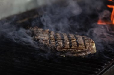 Izgarada alevli biftek var. Izgara ızgara ızgara ve seçici odaklı çekim.