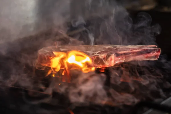 Beef steaks on the grill with flames. Grilling steaks on flaming grill and shot with selective focus.