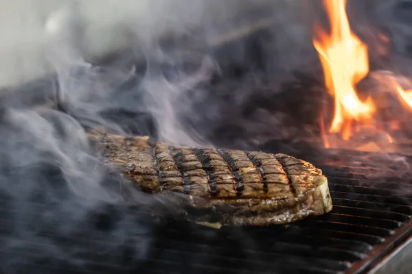 Beef steaks on the grill with flames. Grilling steaks on flaming grill and shot with selective focus.