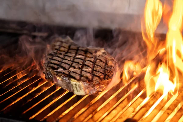 Beef steaks on the grill with flames. Grilling steaks on flaming grill and shot with selective focus.