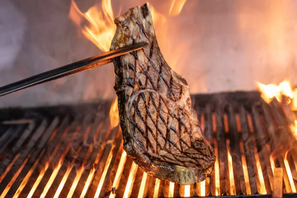 Beef steaks on the grill with flames. Grilling steaks on flaming grill and shot with selective focus.