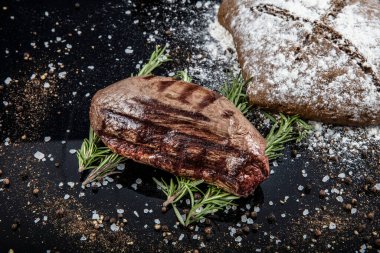 Siyah ahşap bir yüzey üzerinde ızgara fileminyon bifteği.