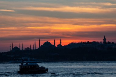 İstanbul Boğazı 'nda Ayasofya' nın siluetiyle Mavi Cami 'nin üzerinde güneş batıyor.