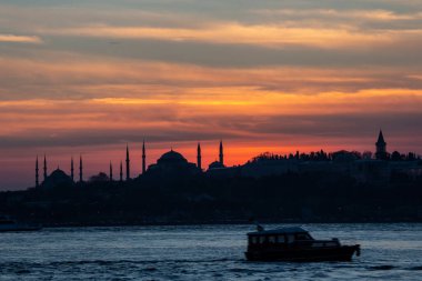 İstanbul Boğazı 'nda Ayasofya' nın siluetiyle Mavi Cami 'nin üzerinde güneş batıyor.