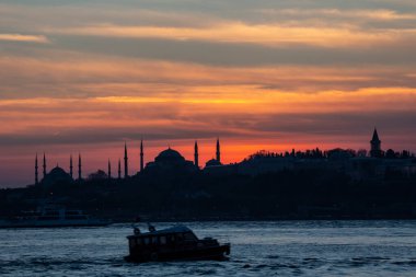 İstanbul Boğazı 'nda Ayasofya' nın siluetiyle Mavi Cami 'nin üzerinde güneş batıyor.