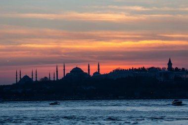 İstanbul Boğazı 'nda Ayasofya' nın siluetiyle Mavi Cami 'nin üzerinde güneş batıyor.