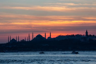 İstanbul Boğazı 'nda Ayasofya' nın siluetiyle Mavi Cami 'nin üzerinde güneş batıyor.