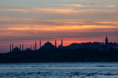 İstanbul Boğazı 'nda Ayasofya' nın siluetiyle Mavi Cami 'nin üzerinde güneş batıyor.