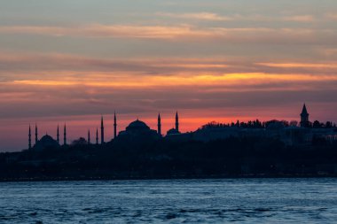 İstanbul Boğazı 'nda Ayasofya' nın siluetiyle Mavi Cami 'nin üzerinde güneş batıyor.