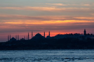 İstanbul Boğazı 'nda Ayasofya' nın siluetiyle Mavi Cami 'nin üzerinde güneş batıyor.