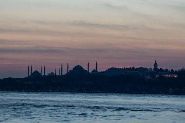 İstanbul Boğazı 'nda Ayasofya' nın siluetiyle Mavi Cami 'nin üzerinde güneş batıyor.