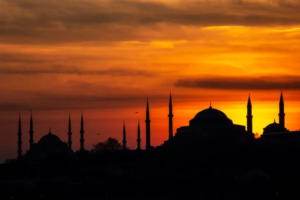 Sun setting over Blue Mosque with Hagia Sophia in silhouette on the Bosphorus Istanbul.