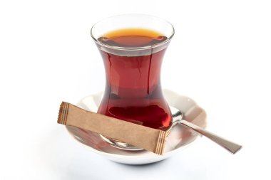 Bir bardak kırmızı şarap ve beyaz arka planda bir kaşık çay.