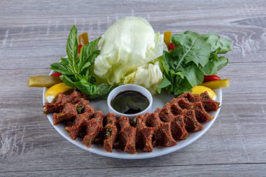 Porselen tabakta limonlu, marullu ve maydanozlu Türk Cig Kofte. 