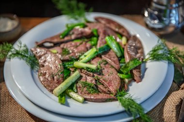 Tabakta yeşil sebzeli kuzu ciğeri yemeği ve restoran ve mutfak konsepti için ahşap masada yerel ekmek.. 