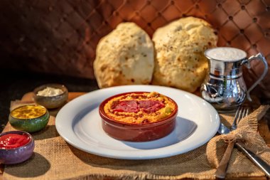 Kimyon, zeytin yağı ve pastirma ile nohut sarısı humus, tereyağı, gri arka planda seramik koyu kâsede servis edilir. Geleneksel Arap yemekleri. Vejetaryen sağlıklı akşam yemeği..